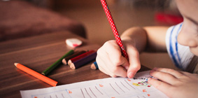 Une élève écrit avec un crayon de plomb.